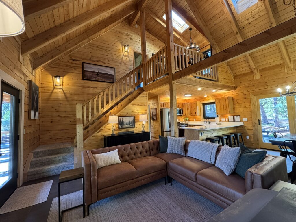 27 Rustic Modern Living Room Ideas to Create a Cozy Cabin You'll Never Want to Leave Rustic modern living room with leather sectional sofa, stone fireplace, vaulted wood ceiling, cozy cabin decor, and warm mountain style.